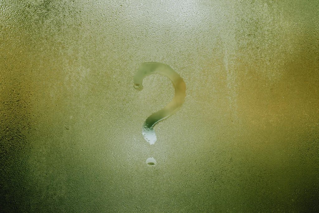 A question mark drawn on foggy glass, evoking curiosity and mystery.
