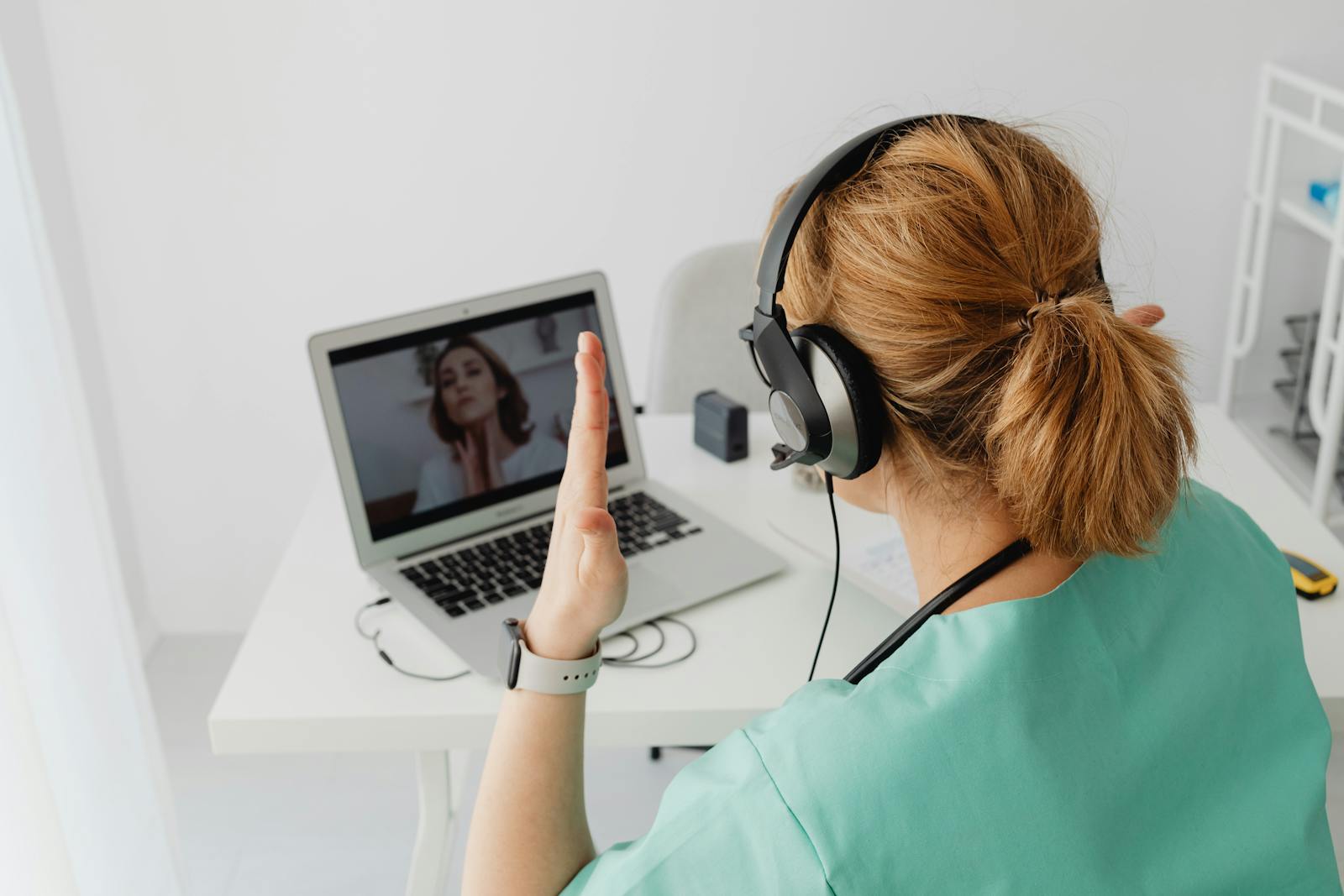 A female doctor engaged in a video call consultation with a patient on a laptop.