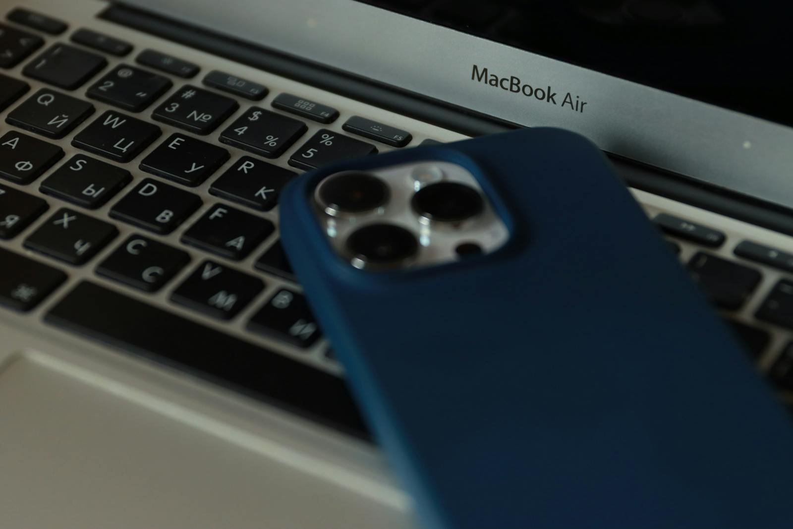 A close-up of a MacBook Air and an iPhone, showcasing modern technology in an office setting.