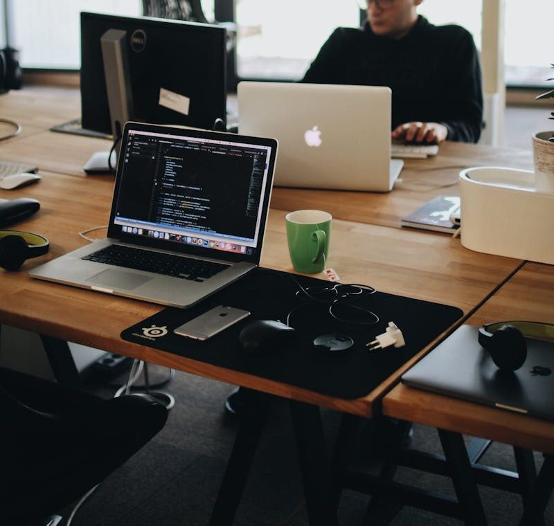 A web developer working on code in a modern office setting with multiple devices.