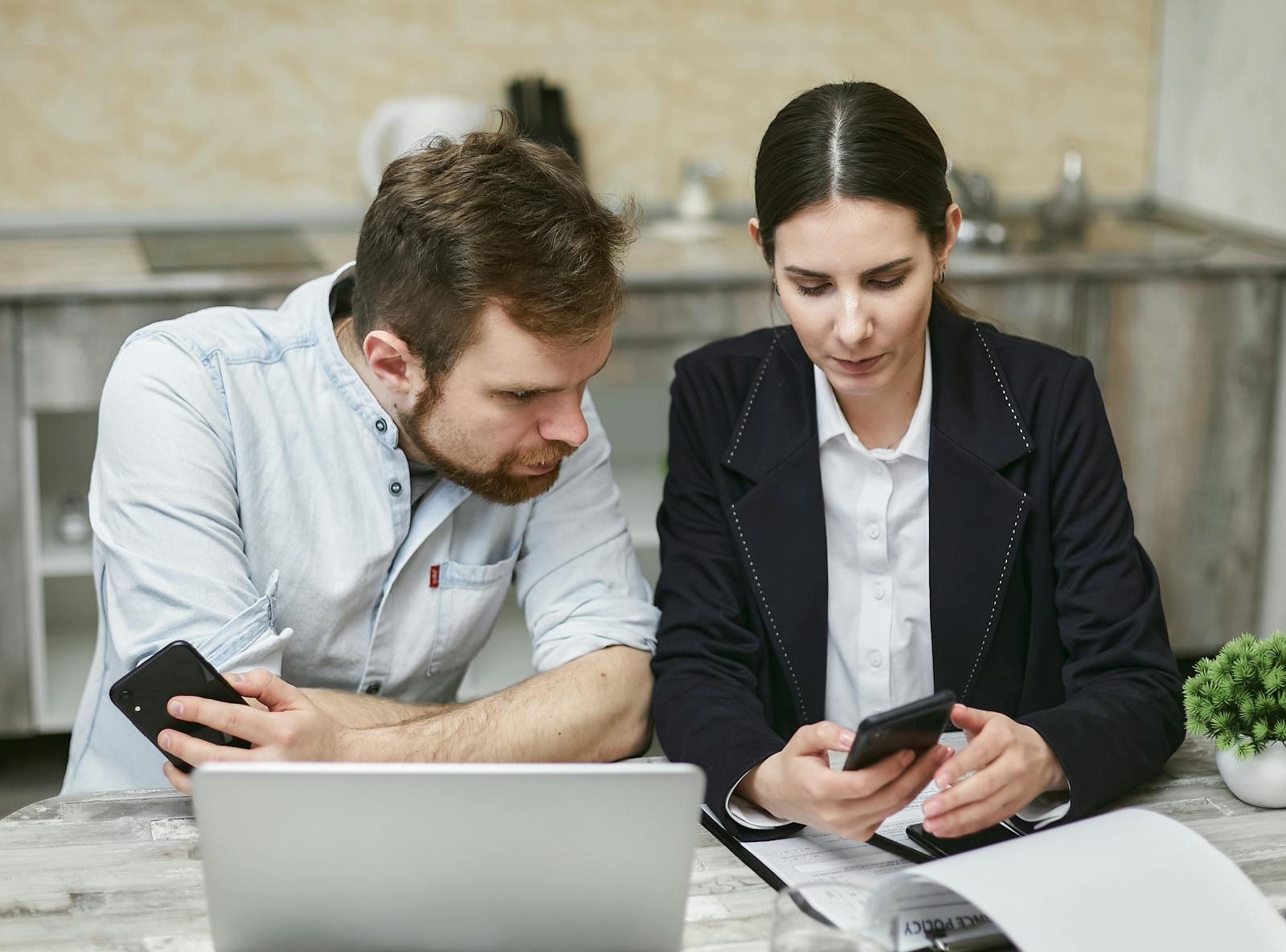 Business professionals working together using smartphones and a laptop in a modern office.